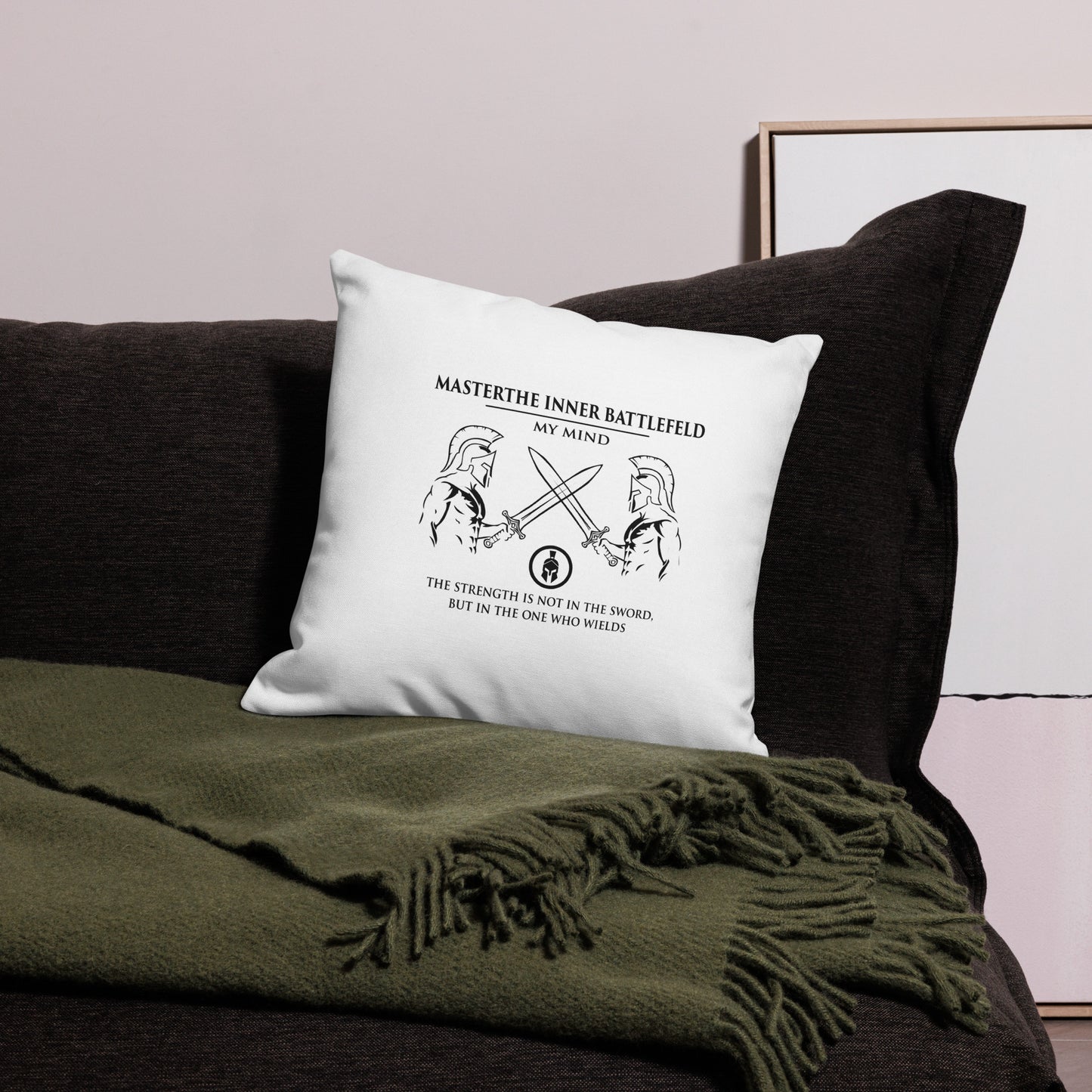 White pillow with motivational quote on a dark couch with green blanket